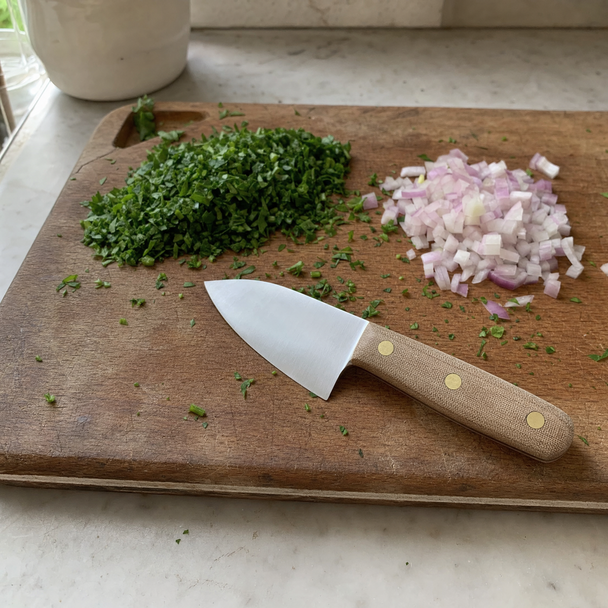 The Chef 165 on a wooden board beside chopped parsley and diced shallot.
