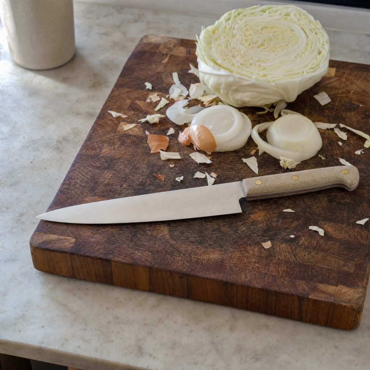 The Chef 200 resting on a worn end-grain board beside a halved cabbage and sliced onion.