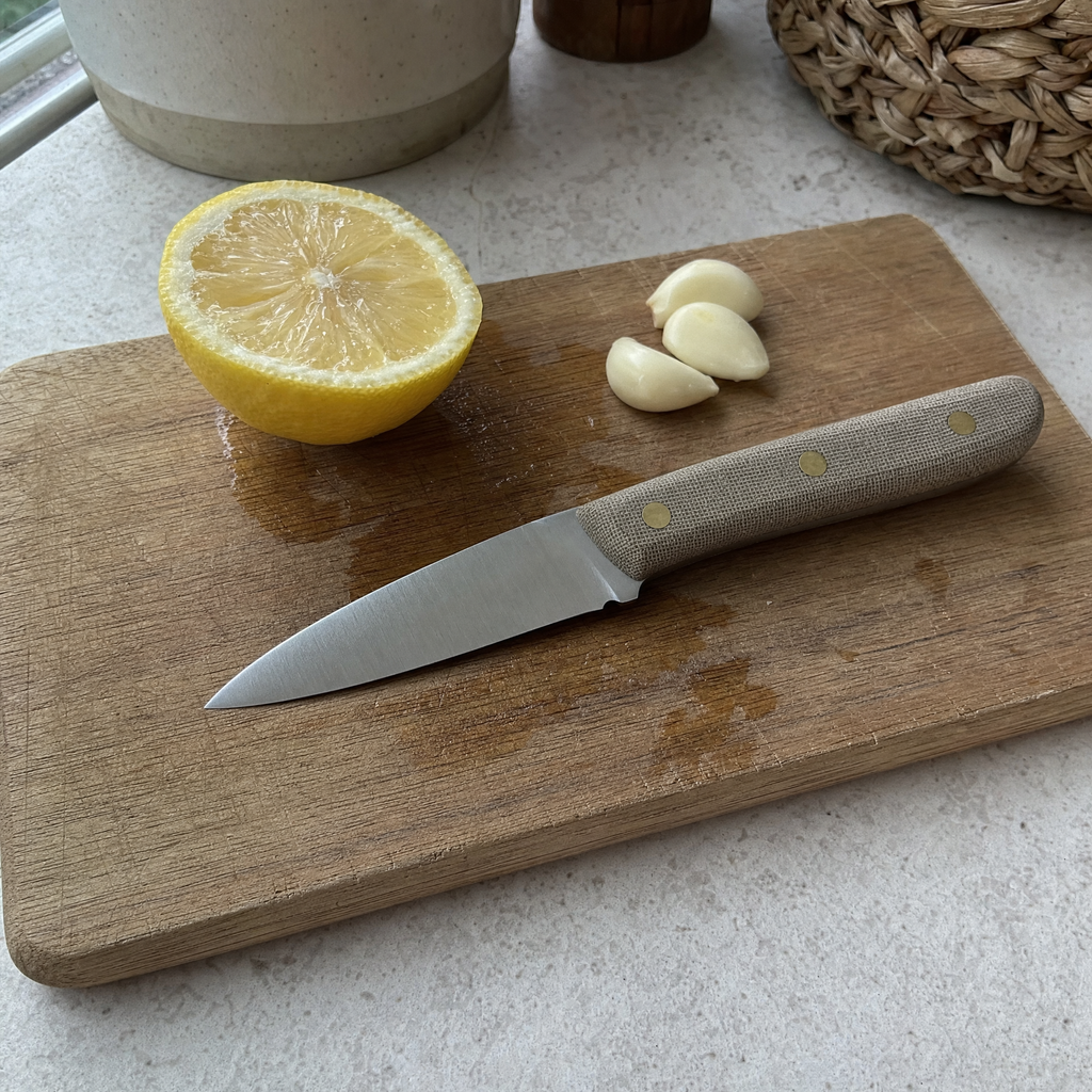 The Prep 130 on a wooden board beside a halved lemon and peeled garlic cloves.